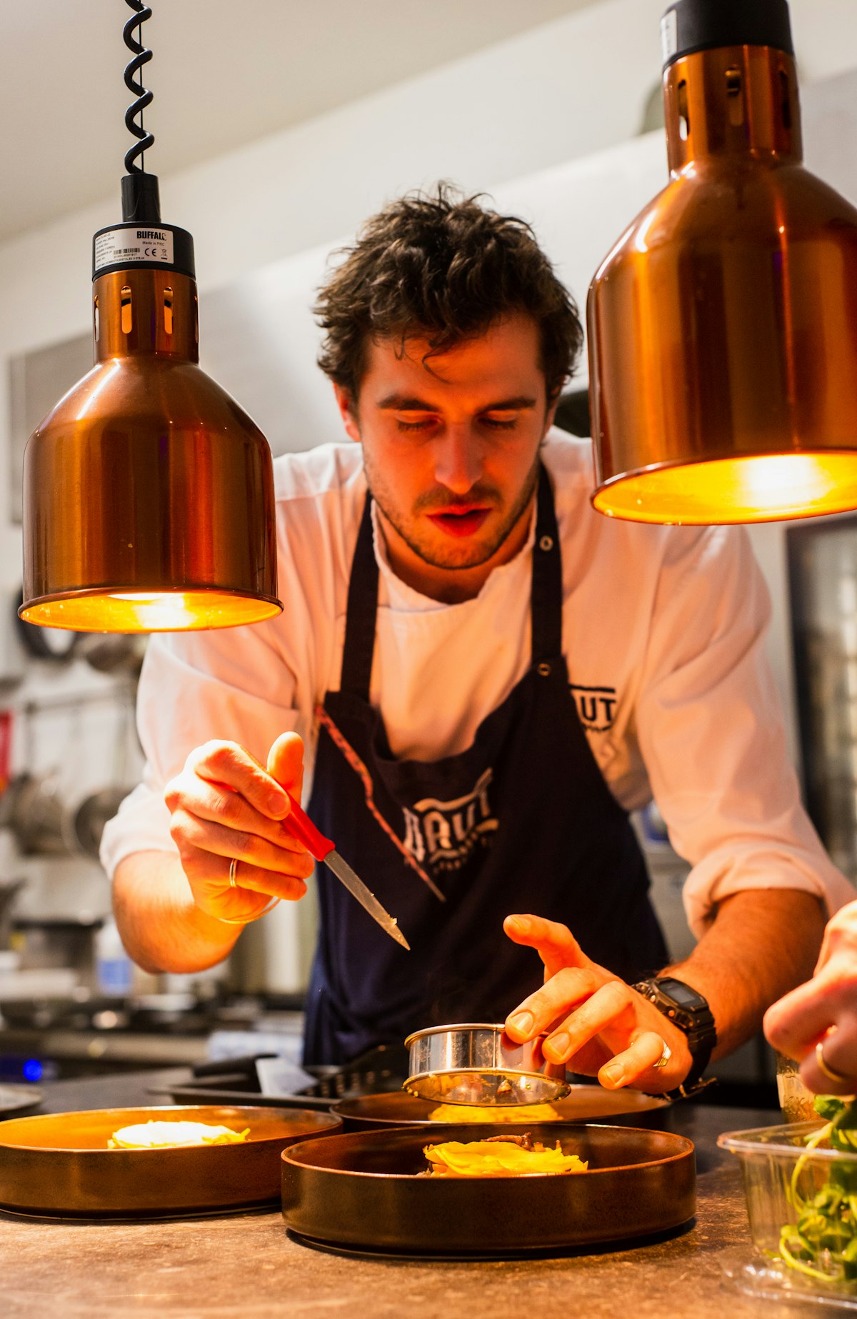 Cozinheira a finalizar um prato junto à brasa