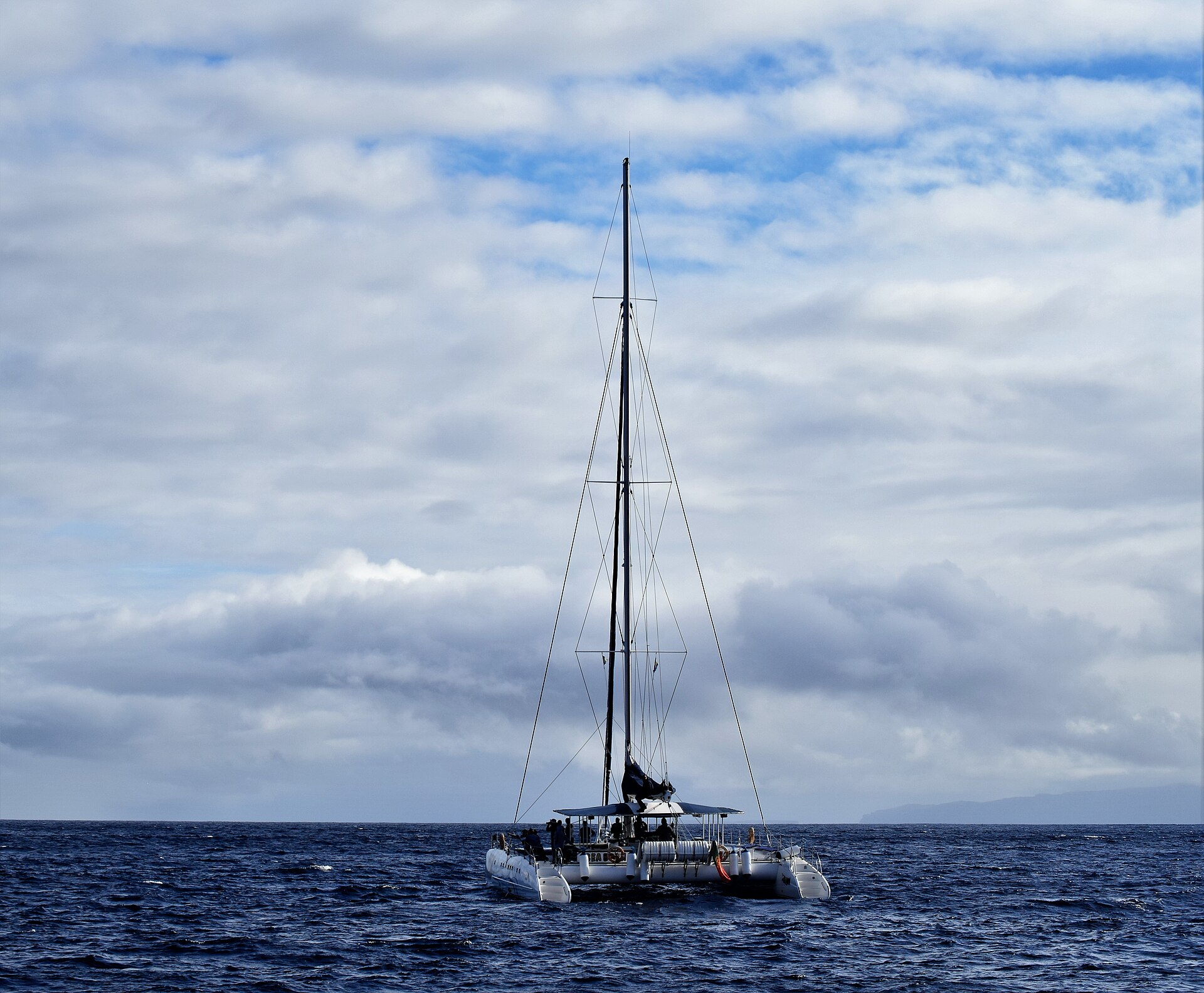 A sailing catamaran head to wind on open Atlantic water under a dramatic sky
